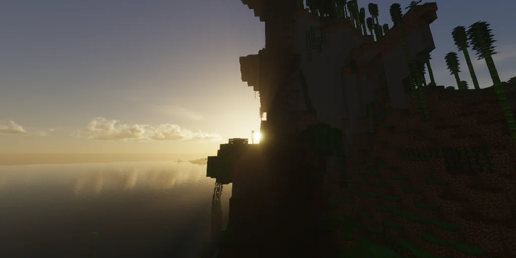 Sun setting behind a large cliff with trees overlooking a hazy ocean